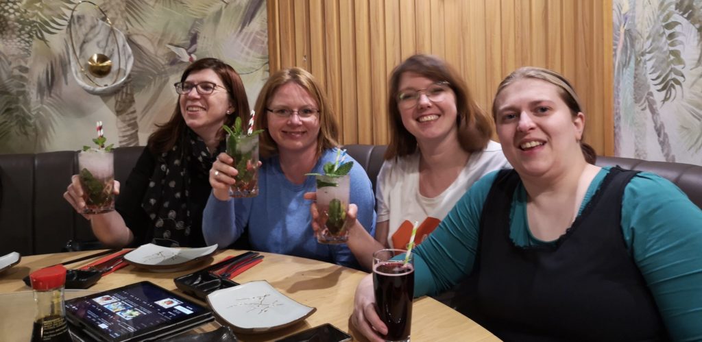 Vier Frauen mit Getränken, lächelnd im Restaurant