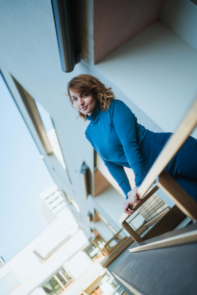 Frau in blauem Pullover, die auf einem Balkon steht